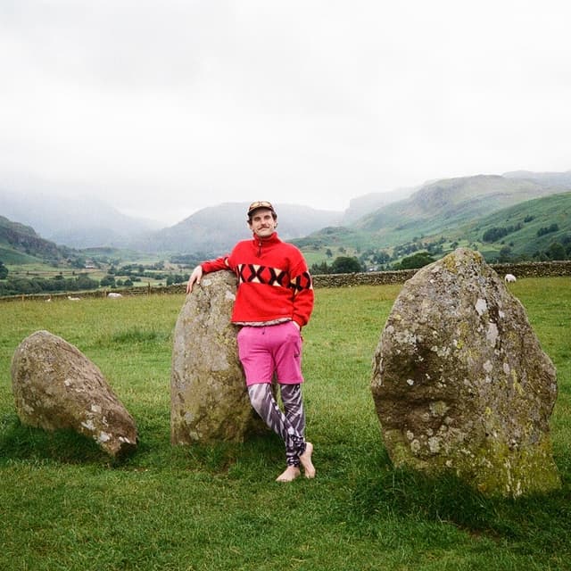 portrait of Tom Glencross beside some neolithic standing stones